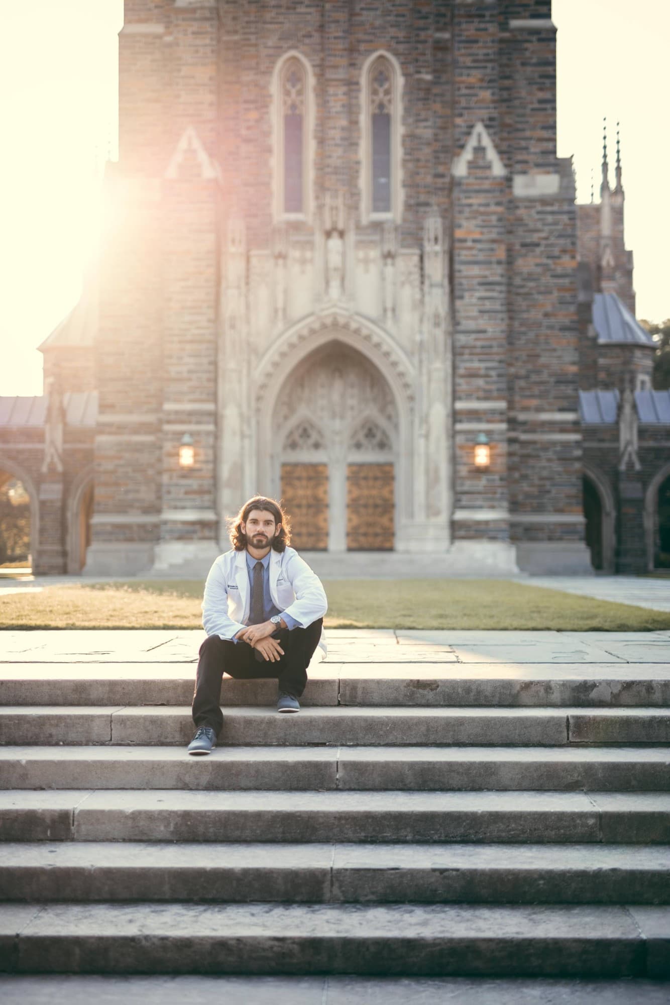 Dr. Nadim in a white coat on the steps of Duke Chapel